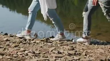 两个徒步旅行者沿着湖的岩石海岸散步