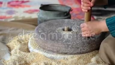 女人用手在石磨里磨麦子