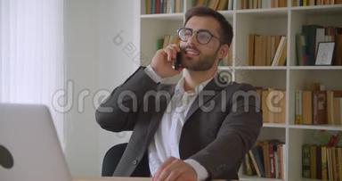 戴眼镜、坐在笔记本电脑前打电话的成年白种人成功商人的特写镜头