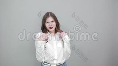 失望的年轻女子穿着白色衬衫，双手摊在灰色的墙上