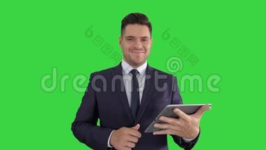 英俊的男人在平板电脑上<strong>翻页</strong>，在绿色屏幕上微笑着对着相机，键。