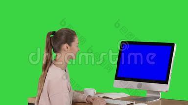 女孩坐在<strong>电脑显示器</strong>前，看着绿色的蓝色屏幕模型显示