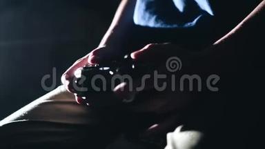 儿童用控制器`手的特写。 这个男孩玩电子游戏。 黑暗的房间。