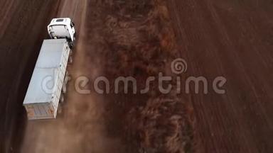 卡车正沿着犁田间的土路行驶。