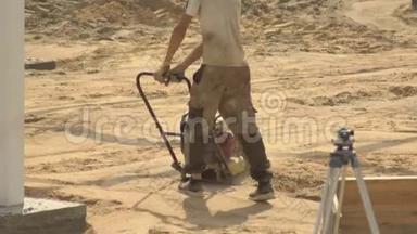 一名男工人在铺设瓷砖的道路<strong>施工</strong>过程<strong>中</strong>夯实沙子。 土壤凝结设备，<strong>建筑</strong>