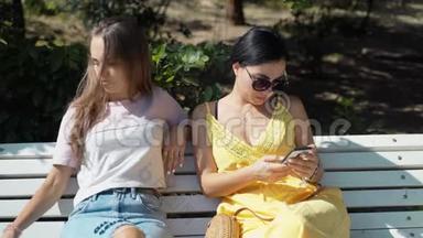 两个年轻女孩看着手机，然后开始看书。