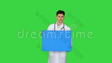 微笑的男医生戴着听诊器，在绿色屏幕上举着空白海报，Chroma键。