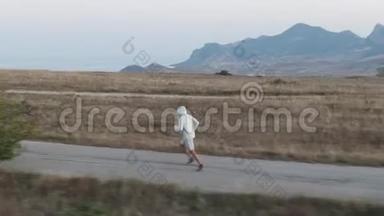 黎明时分在山上慢跑一个穿短裤的人在柏油路上奔跑，背景是山、海和