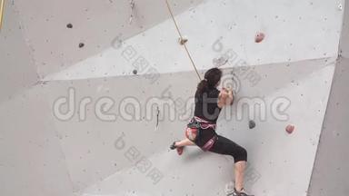 年轻女子在室内攀岩墙上锻炼。 慢动作。 在攀岩墙上训练登山者。 女孩
