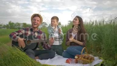 快乐的爸爸演奏<strong>乐器</strong>，而妈妈和儿子一起在大自然的家庭野餐中尽情享受和<strong>鼓</strong>掌