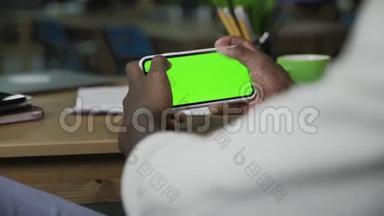 非裔美国人手在带有绿色屏幕的水平智能手机上滚动网页