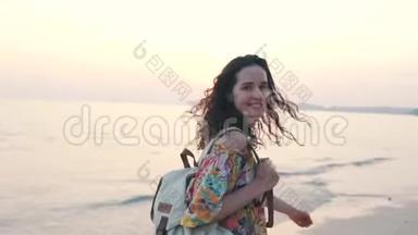 日落时带背包的女孩在海滩上散步