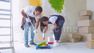<strong>家</strong>庭<strong>装修</strong>：年轻的幸福夫妇用油漆滚筒粉刷他们的新房子内部