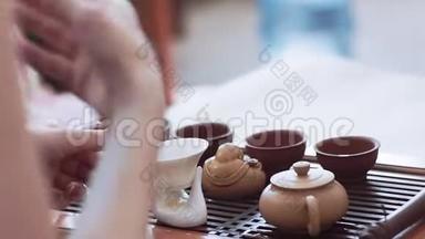 女孩举行茶道，教如何冲泡茶。 桌子上有杯子、雕像和茶壶