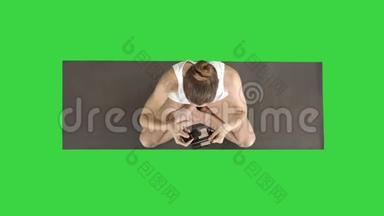 <strong>瑜伽女人在做</strong>化妆时，坐<strong>在</strong>莲花姿势上的绿色屏幕，铬键。