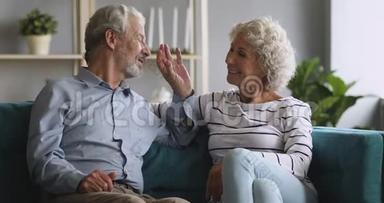 快乐的老爷爷奶奶夫妇放松谈话笑坐在沙发上