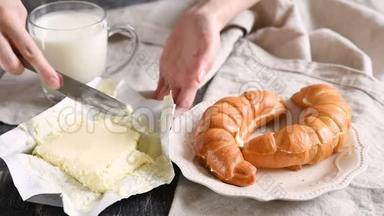 女人把黄油涂在新鲜牛角面包上。 欧式早餐