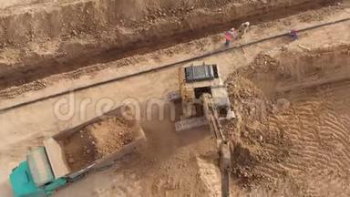 挖掘机将土壤装载到运输卡车上，顶部向下的空中镜头