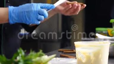女厨师在烤面包上涂黄油的特写镜头。 餐厅小吃烹饪。 面包和黄油。 双手戴蓝手套