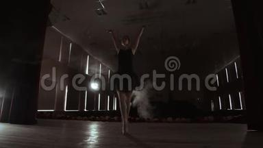 年轻美丽的芭蕾舞演员在烟雾舞台上跳舞的现代芭蕾舞。 用手进行平稳的动作.