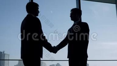 商务人员在办公室的窗口握手，互相拍拍肩膀