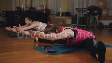 两个女孩做伸展运动。 女孩坐在地板上<strong>劈叉</strong>，双手伸到脚边