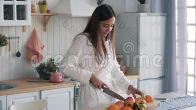 穿着白色浴袍的可爱女孩在厨房里穿着橙色衣服