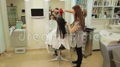 专业设计师用吹风机吹干她的女客户的头发。