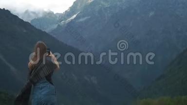 年轻迷人的女孩旅行者-博客制作了一张大山的照片在智能手机上。 穿着暖和的衣服