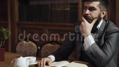 有思想的留胡子的人坐在桌边在<strong>图书馆看书</strong>。 <strong>图书馆</strong>里的聪明人。 智能智能