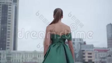 <strong>美丽美丽美丽</strong>的女孩，穿着一件漂亮的晚绿色连衣裙，迷人地走在附近空荡荡的城市广场上