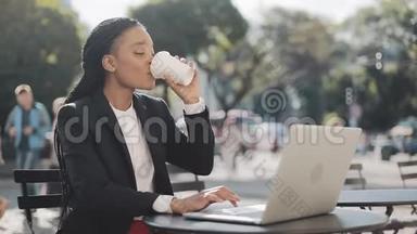 微笑的非裔美国女商人坐在<strong>夏日</strong>露台的<strong>咖啡</strong>馆里，喝着<strong>咖啡</strong>，在视频上交谈