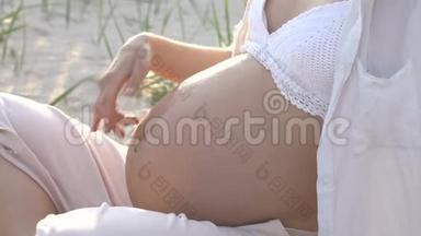 怀孕后期，孕妇用手<strong>轻轻地</strong>、慈爱<strong>地</strong>抚摸着腹部