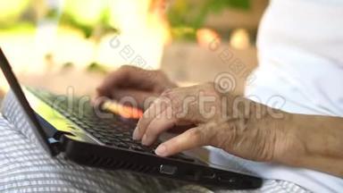 手的特写镜头。 中年妇女在户外工作，手提电脑，微笑的中年祖母在远处工作