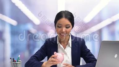 快乐的女士摇着<strong>小猪储蓄罐</strong>，微笑着，为未来进行有利可图的投资