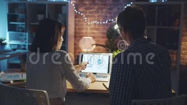 女孩和男人的智能手机界面设计师在办公室工作的笔记本电脑