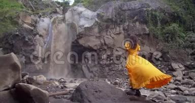 穿着黄色长裙的女人欣赏高山瀑布，急速的海水从岩石中<strong>坠落</strong>，大自然的可怕力量