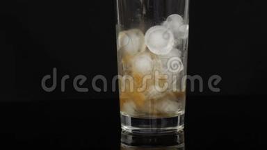 <strong>可乐</strong>被<strong>倒</strong>进一个大的长玻璃杯里，里面有一块黑色的背景上的冰。