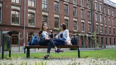 快乐的女<strong>学生</strong>在上课前坐在校园公园的长凳上<strong>聊天</strong>。 大学朋友