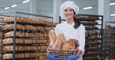 食品厂微笑着，一位美丽的大女士在烘焙区，她拿着一个新鲜的烘焙面包，直视着。