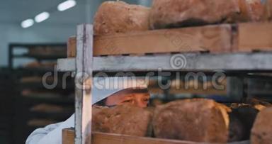 漂亮的厨师面包师闻起来非常热情，新鲜的有机面包很高兴，她从面包里拿了一些面包。