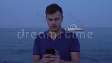 晚上，年轻男子在海滨游轮上使用智能手机，并以此为背景
