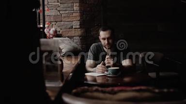 有着胡茬和纹身手臂的野蛮人坐在咖啡馆里做笔记