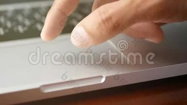 4K. 特写一个男人用手提笔记本电脑，用手指用键盘和触摸板或触控板滑动和放大，放大