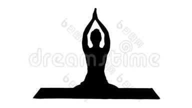 剪影放松的女人在瑜伽的位置，把手放在一起，冥想。