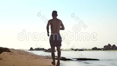 男人沿着沙滩奔跑，快乐的狗慢慢地奔跑