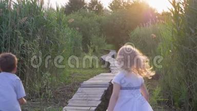 户外娱乐活动，活跃的小朋友，女孩和男孩在绿色的大自然中玩追赶和在木桥上奔跑