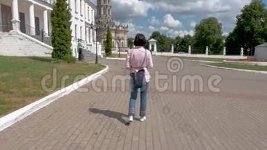 一位穿着粉红色衬衫和蓝色裤子的中年妇女在这个历史遗址上走来走去。