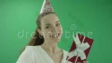 令人惊讶的兴奋的女人笑着，戴着<strong>生日帽</strong>展示了一件礼物。 她穿正装. 女士站得很近