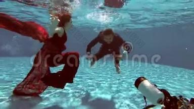 水下摄影师把新娘和新郎穿着婚纱在水池底部的水下拍摄
